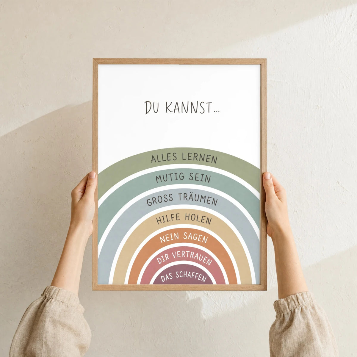 Affirmationsposter „Regenbogen Du kannst“ im Holzrahmen in den Händen gehalten – Taufgeschenk und Kinderzimmer Deko
